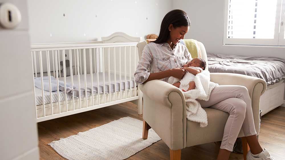 mom holding newborn in baby room