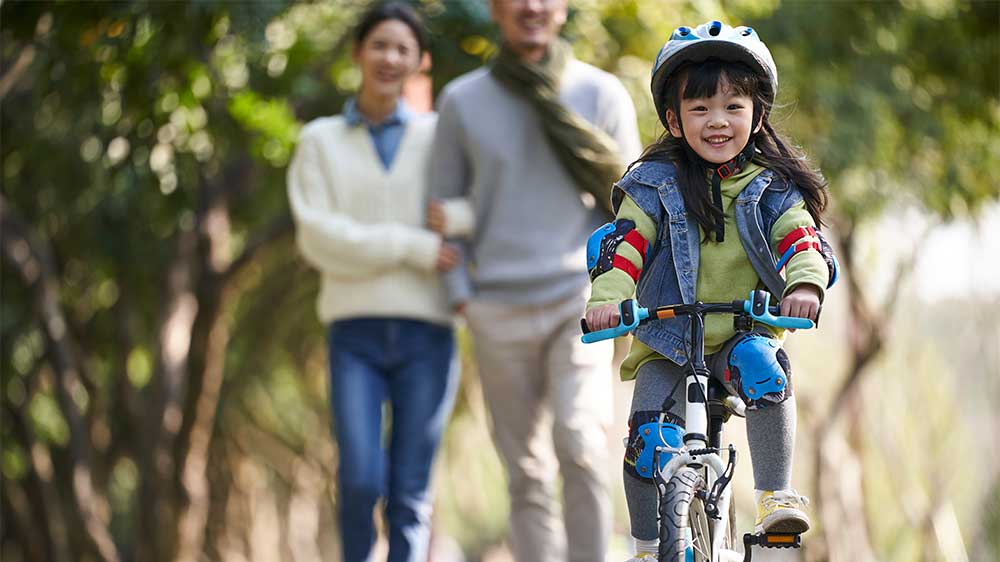 child riding bike with parents watching