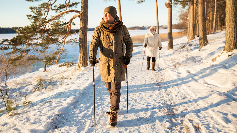 two adults on snowy path with walking poles